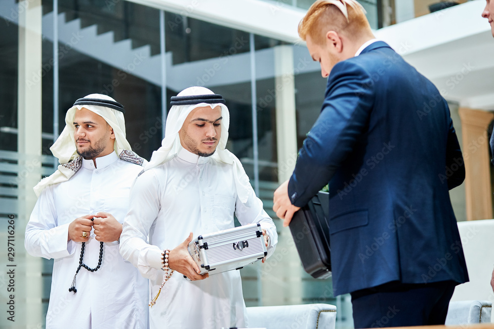 Obraz premium Arabic businessman give money for barter, buy new technology by caucasians