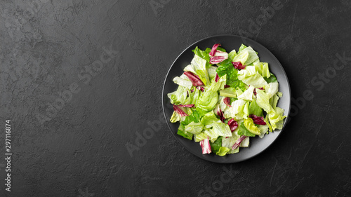 Vegetable salad with iceberg lettuce, romaine and radicchio salad on black background. Healthy food. Top view with copy space. photo
