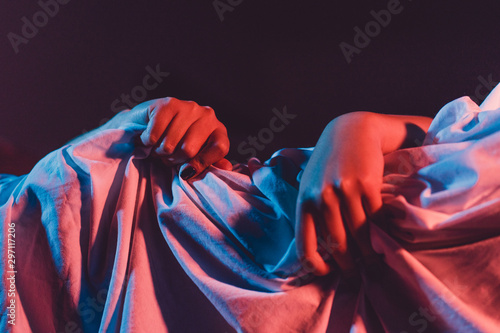 Fotografie Female hand squeezing bed sheet in dark room love passion concept woman hands cl