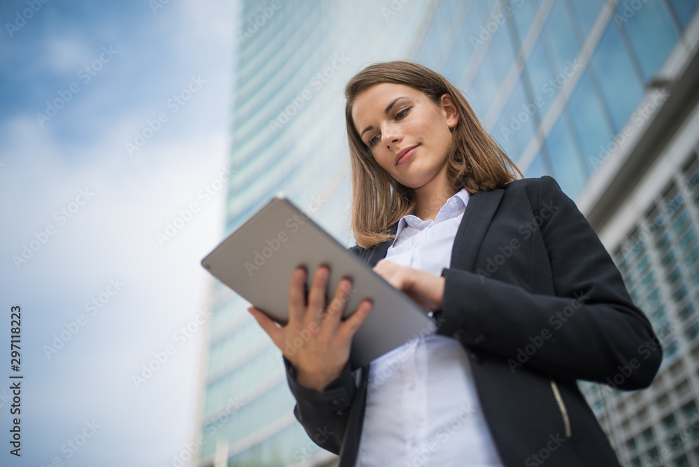 Woman using a tablet in front of her office Woman using a tablet in front of her office
