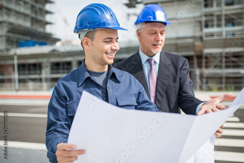 Architect talking to the site manager in front of a construction site building