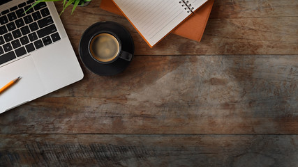 Flat lay office desk with laptop, notebook, pencil, plant and espresso on old rustic wood table.