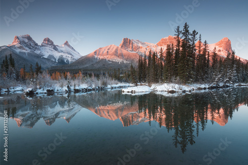 First snow Almost near perfect reflection of the Three Sisters Peaks in the Bow River. Canmore in Banff National Park Alberta Canada Snow-covered winter mountain in a winter atmosphere. Beautiful day