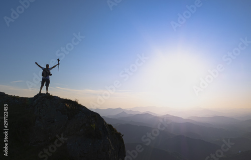 man at the top celebrating success with the sun in the background