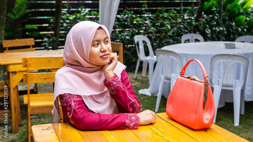 A portrait of beautiful young Muslim Malay woman wearing a hijab and modern traditional dress called 