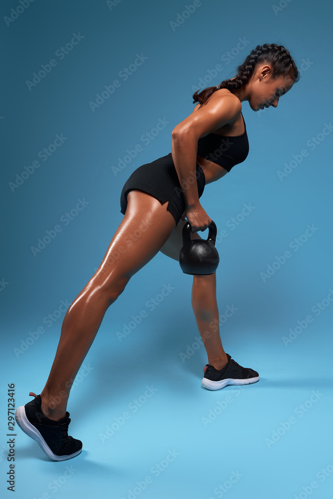 full-body kettlebell workout for beginners,physical development, fitness training program. cross fit. full length back view photo. isolated blue background.