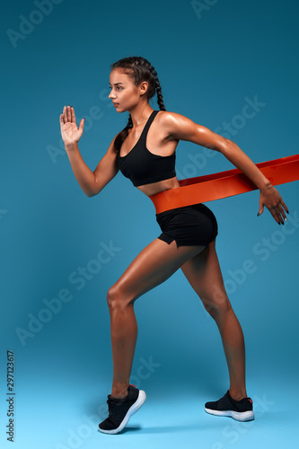 motivated awesome slim woman exercising fitness resistance bands, full length side view photo. isolated blue background, studio shot. lifestyle