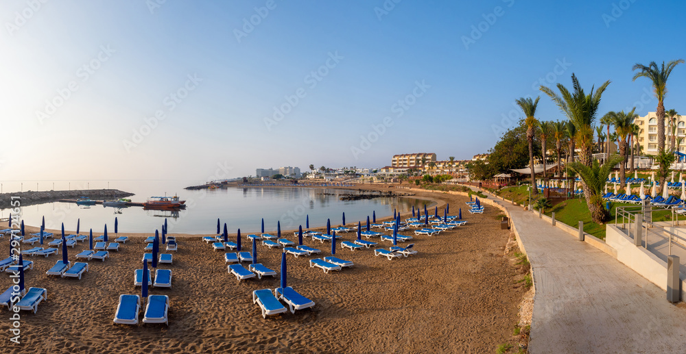 Panorama Of Cyprus. Pernera. Beach holidays in the Mediterranean. Kalamies beach. Beach with blue sunbeds and umbrellas. Sandy coast of the Mediterranean sea.
