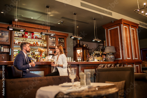 Close up of lovely couple drinking delicious wine at bar counter in pleasant restaurant  talking kindly  attractive young woman listening enterprising man with upset expression