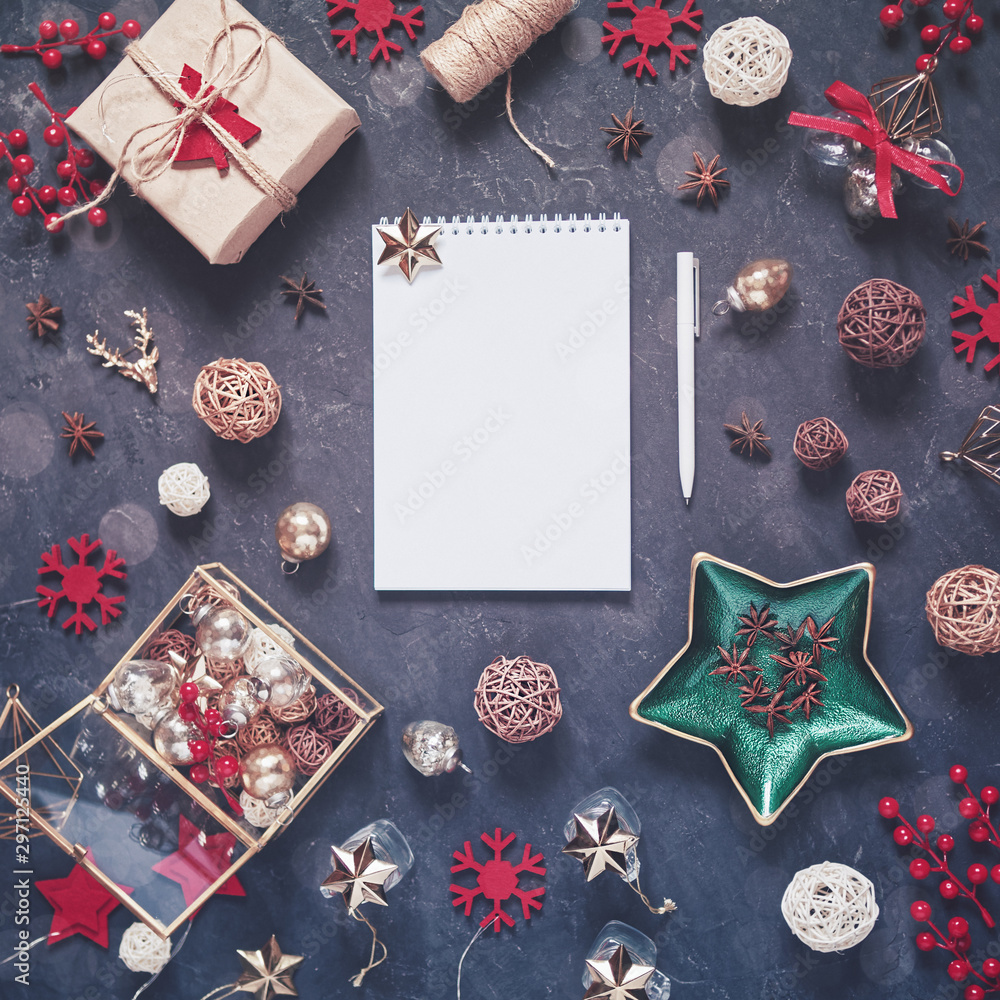 A notepad with blank pages is in the center of the composition between the Christmas decorations. Nearby is a white pen. Planning for the next year, setting goals. A notepad with blank pages is in the center of the composition between the Christmas decorations. Nearby is a white pen. Planning for the next year, setting goals.
