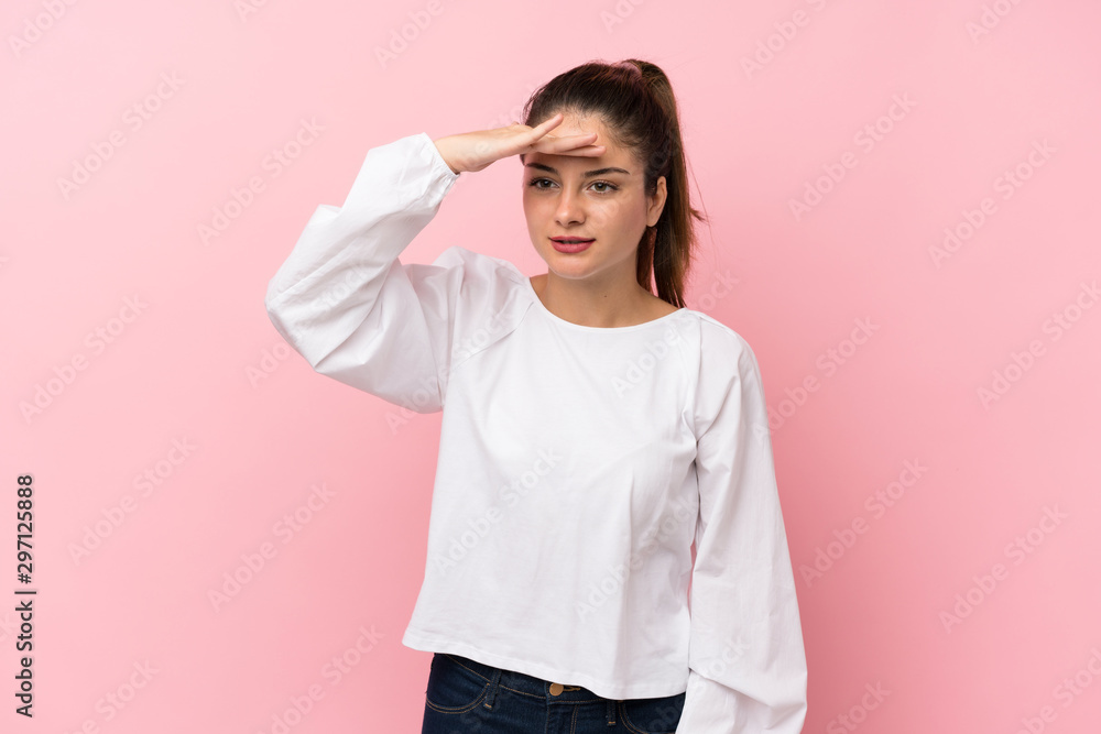 Young brunette girl over isolated pink background looking far away with hand to look something Young brunette girl over isolated pink background looking far away with hand to look something
