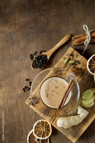 Masala tea in glass on wooden background in rustic style. Traditional Indian hot drink with milk  black tea and spices. Copy space  top view  close-up