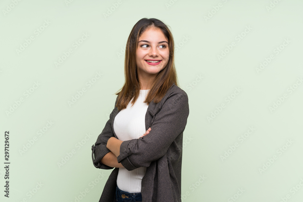 Young brunette girl with blazer over isolated green background with arms crossed and happy Young brunette girl with blazer over isolated green background with arms crossed and happy