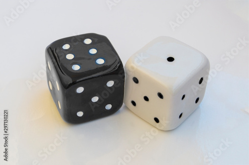 two ceramic dice  one white and one black  isolated on white background