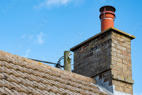 Εκτύπωση καμβά Large, english cottage style brick chimney showing a newly installed terracotta pot together with a chimney cover to prevent birds nesting