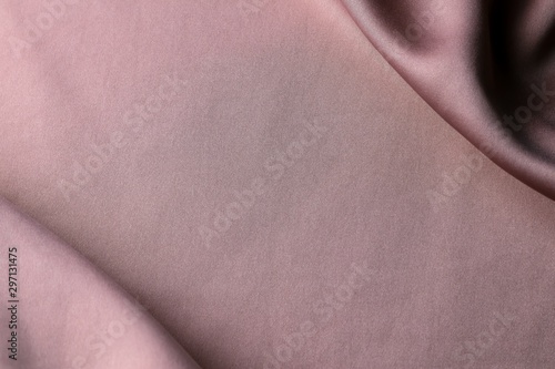 Pink gold satin fabric with crease in corner.