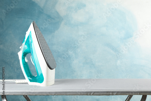 Fotografia, Obraz Iron on ironing board against blue background, space for text