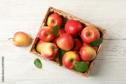Basket with apples on white wooden background, top view