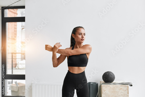 Принти на полотні Slim caucasian female in black sportswear warm-up muscles prapering to do exercises, cross fit