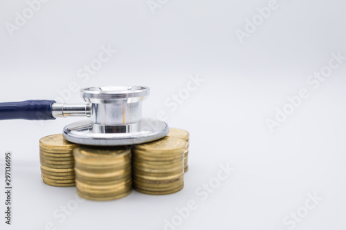 Money, Finance and Health Care concept. Close up of  stethoscope on top of row of stack of gold coins on white background and copy space.