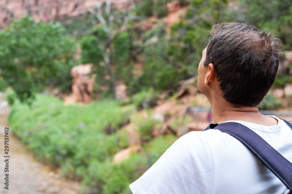 Zion National Park in Utah with man hiker looking at view of Virgin river water with green trees plants from bridge near start of Angel's Landing trail Zion National Park in Utah with man hiker looking at view of Virgin river water with green trees plants from bridge near start of Angel's Landing trail