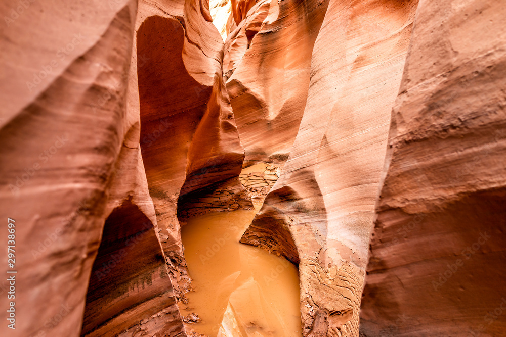 Orange wave sandstone abstract formations view of rocks and muddy dirty water pool at narrow Antelope slot canyon in Arizona on footpath path trail from Lake Powell