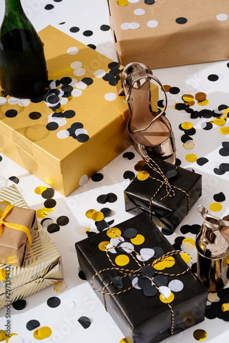 Christmas background with gift boxes, confetti, bottle and glasses of champagne and party shoes. Preparation for holidays and parties. Top view with copy space.