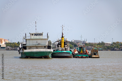 Boats are moored in the middle of Chao Phraya river, Samut Prakan, Thailand.