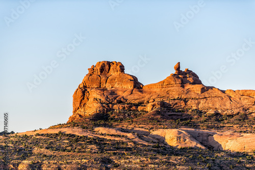 Balanced rock on cliff in Arches National Park butte view in Utah during morning sunrise with orange color