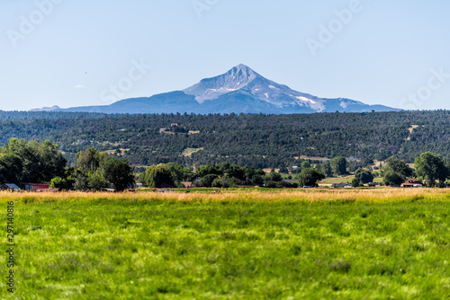 View of Wilson mountain from highway 145 in San Juan region of Colorado with green grass agriculture field on summer sunny day with sky