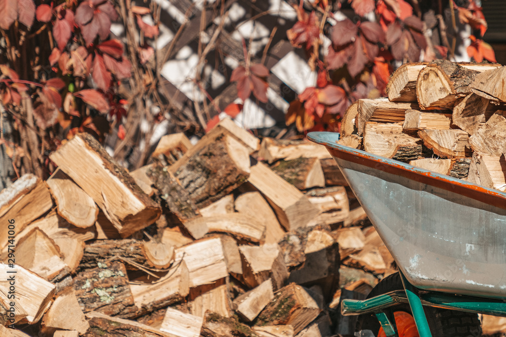 Preparation for the heating season. A cart filled with logs stands next to a pile of firewood. Close up Preparation for the heating season. A cart filled with logs stands next to a pile of firewood. Close up