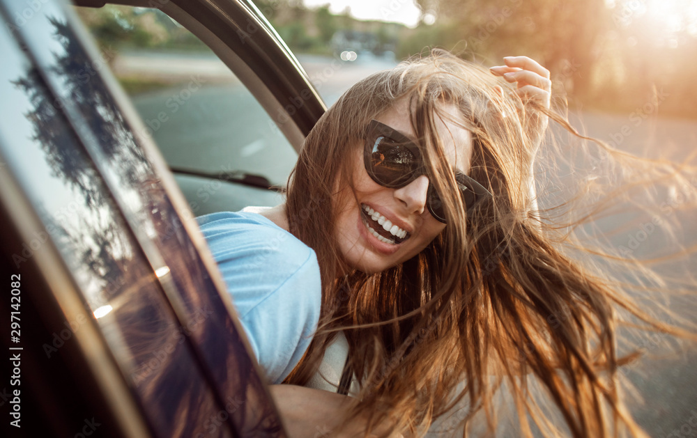 © proimagecontent - Passenger girl's magnificent hair fluttering as she leans out of the car window