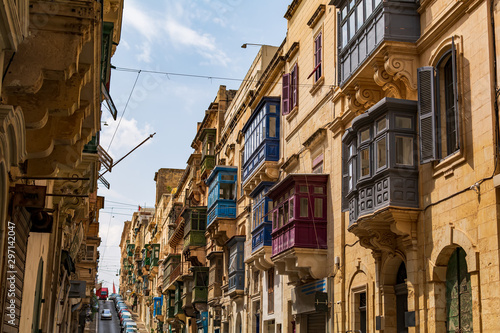 Fototapeta Naklejka Na Ścianę i Meble -  Residential house facade with traditional Maltese multicolored enclosed wooden balconies in Valletta, Malta, in summer day. Authentic Maltese urban scene.