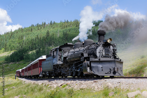 Fototapeta Naklejka Na Ścianę i Meble -  Vintage Steam Train Billowing Smoke as it Moves Through the Mountains.