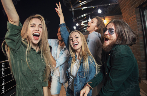 Cheerful friends dancing all night long during their party on a loft balcony