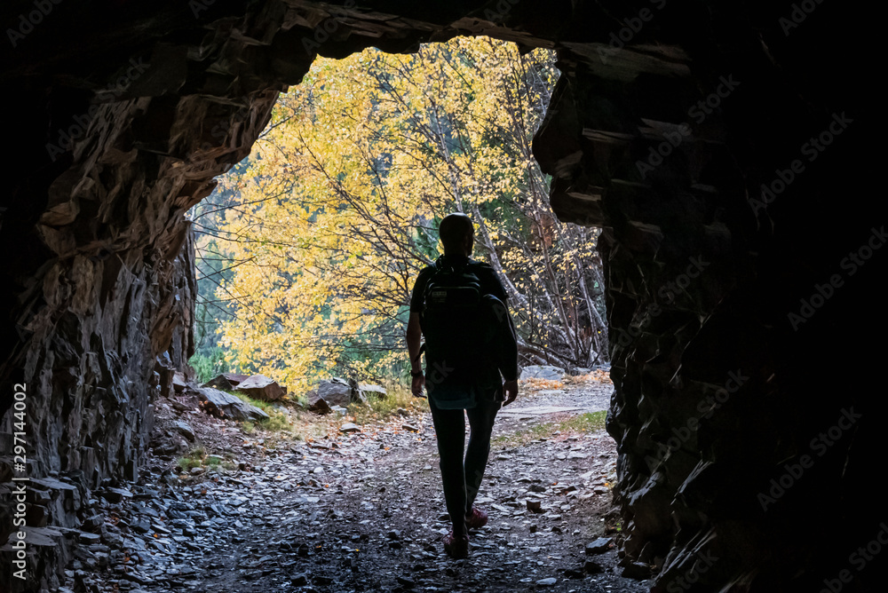 Obraz premium Hombre saliendo de una cueva natural mirando la naturaleza en una montaña