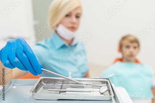 Female dentist woman in blue scrubs picking dental armamentarium © proimagecontent