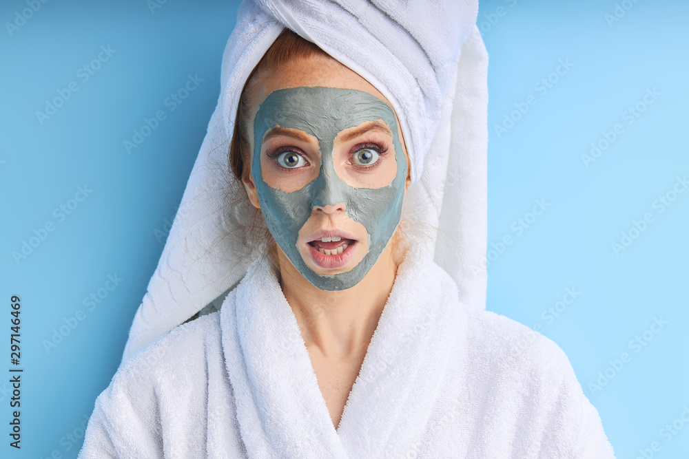 Portrait of young girl with mask for face skin. Isolated over blue background Portrait of young girl with mask for face skin. Isolated over blue background