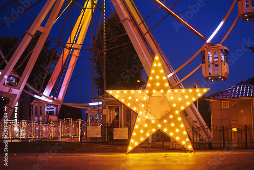 Illuminated glowing star in amusement park at the night city photo