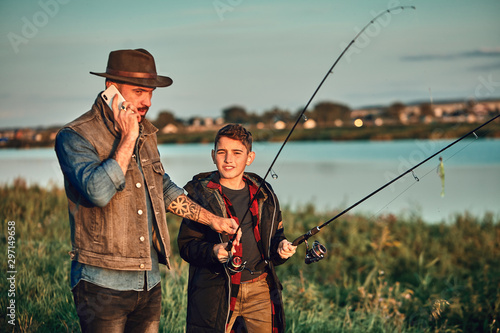 Father and son go fishing. Father takes urgent phone call and gives fishing rod to son