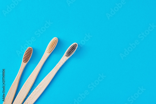 three wooden bamboo toothbrushes on a blue background  top view.  Dental care concept