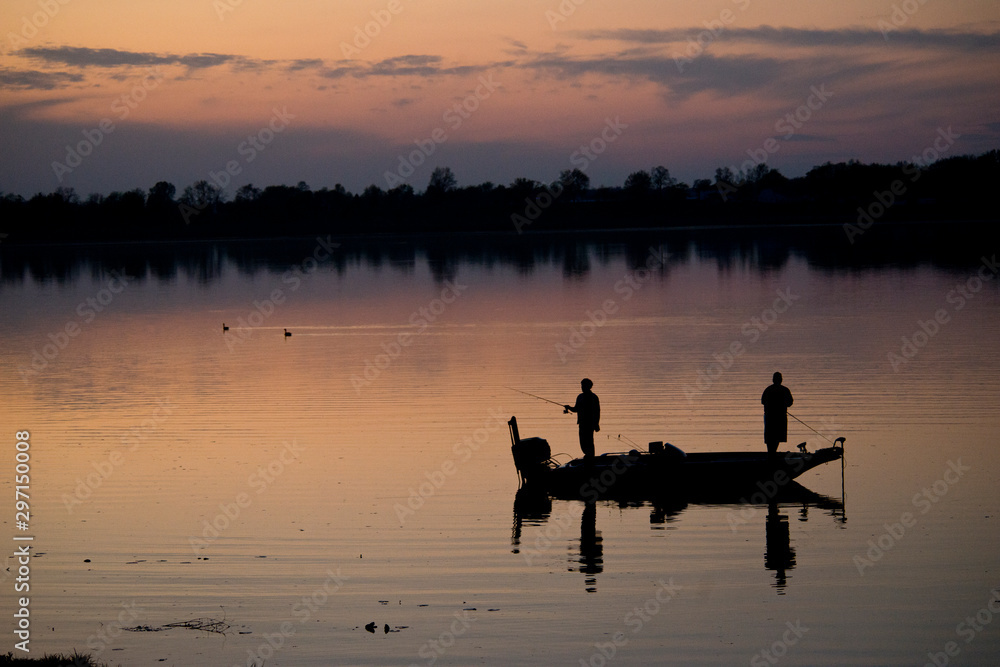silhouette of fishermen on the lake at dusk silhouette of fishermen on the lake at dusk