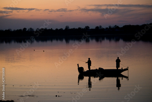 silhouette of fishermen on the lake at dusk