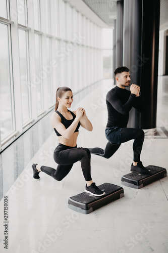 Fit couple working out make squats together at gym