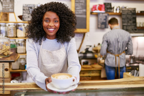 Smiling African American barista holding up a fresh cappuccino