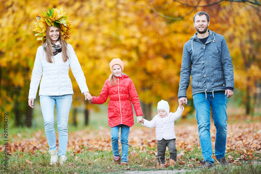 Fototapeta premium Portrait of happy young family with baby girl in autumn park