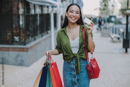 Pretty smiling woman with payment card outdoors