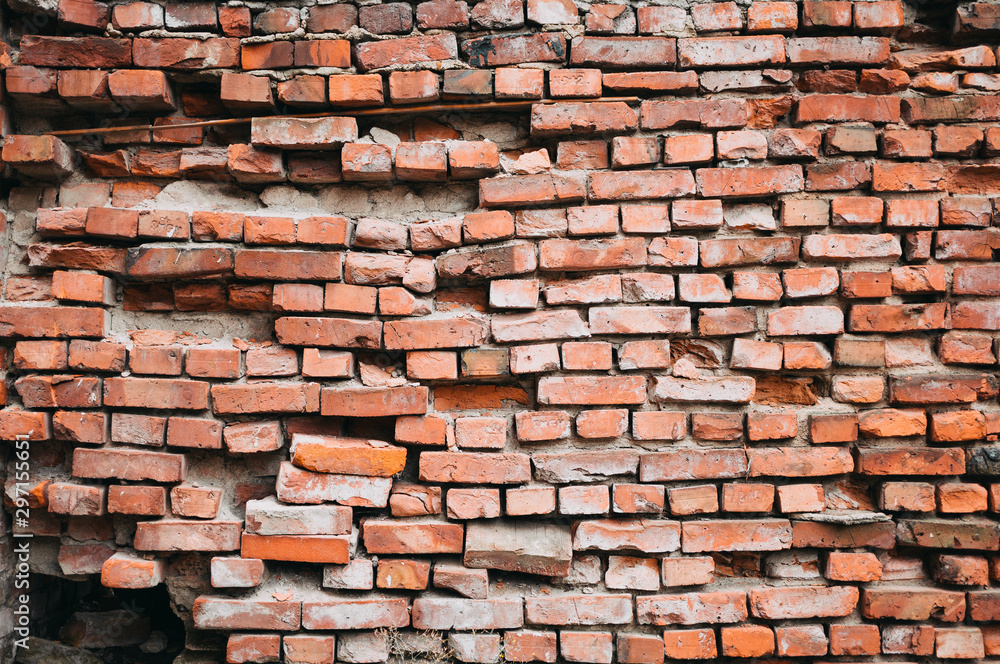 Fototapeta premium A crumbling red brick wall. Vintage background