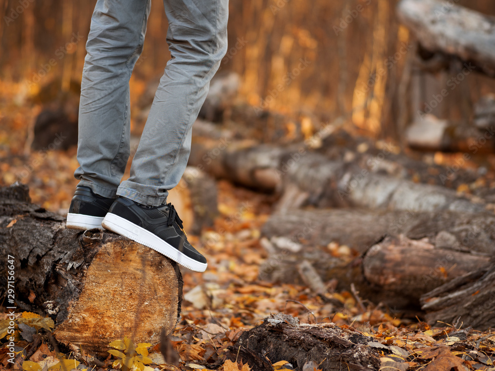 Men's feet in stylish black sneakers in autumn Park or forest. Seasonal shoes Men's feet in stylish black sneakers in autumn Park or forest. Seasonal shoes