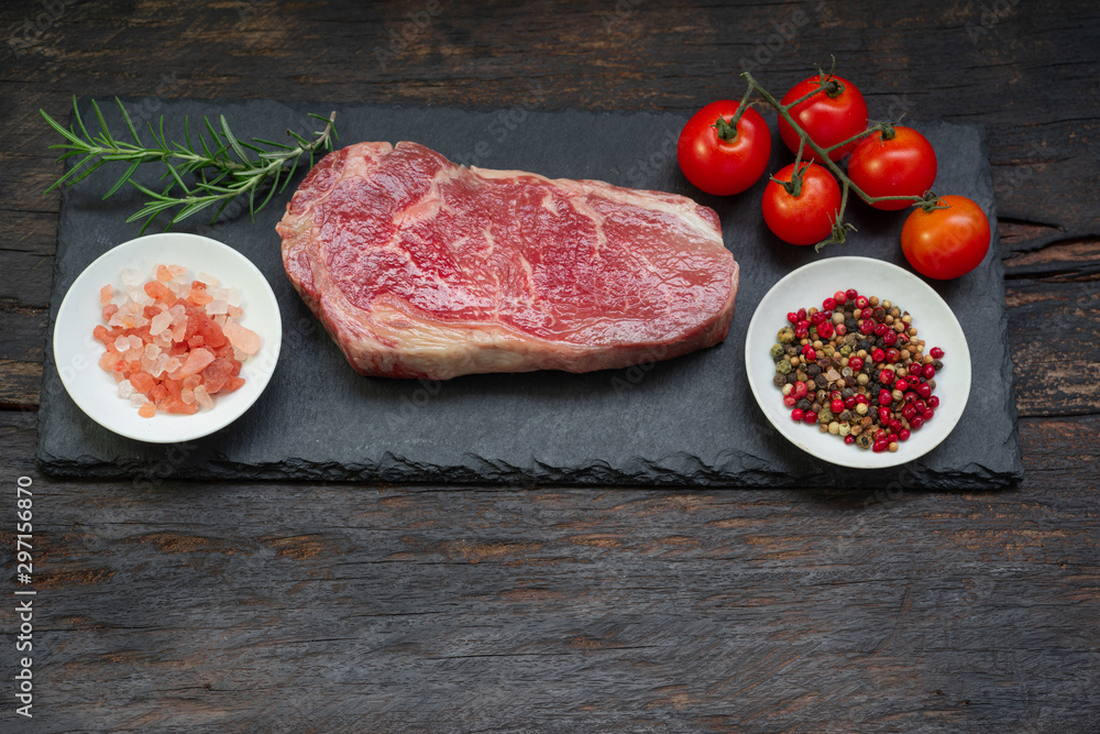 Raw meat, beef steak on black background, top view with spices for grilling